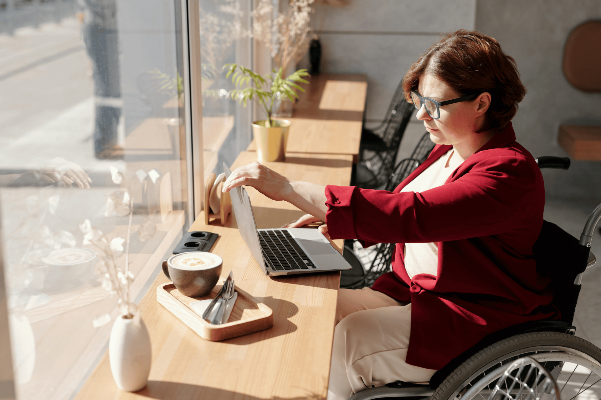 A person in a wheelchair opening a laptop in a cafe