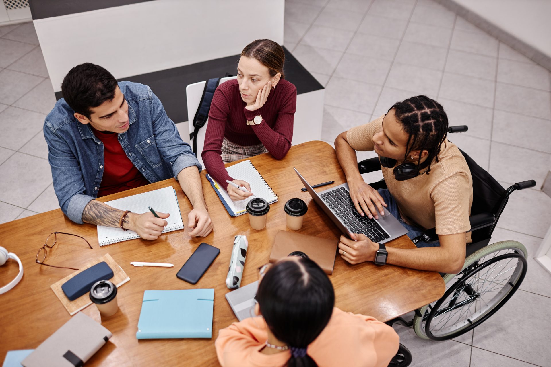 Diverse group of young people studying together in college library.