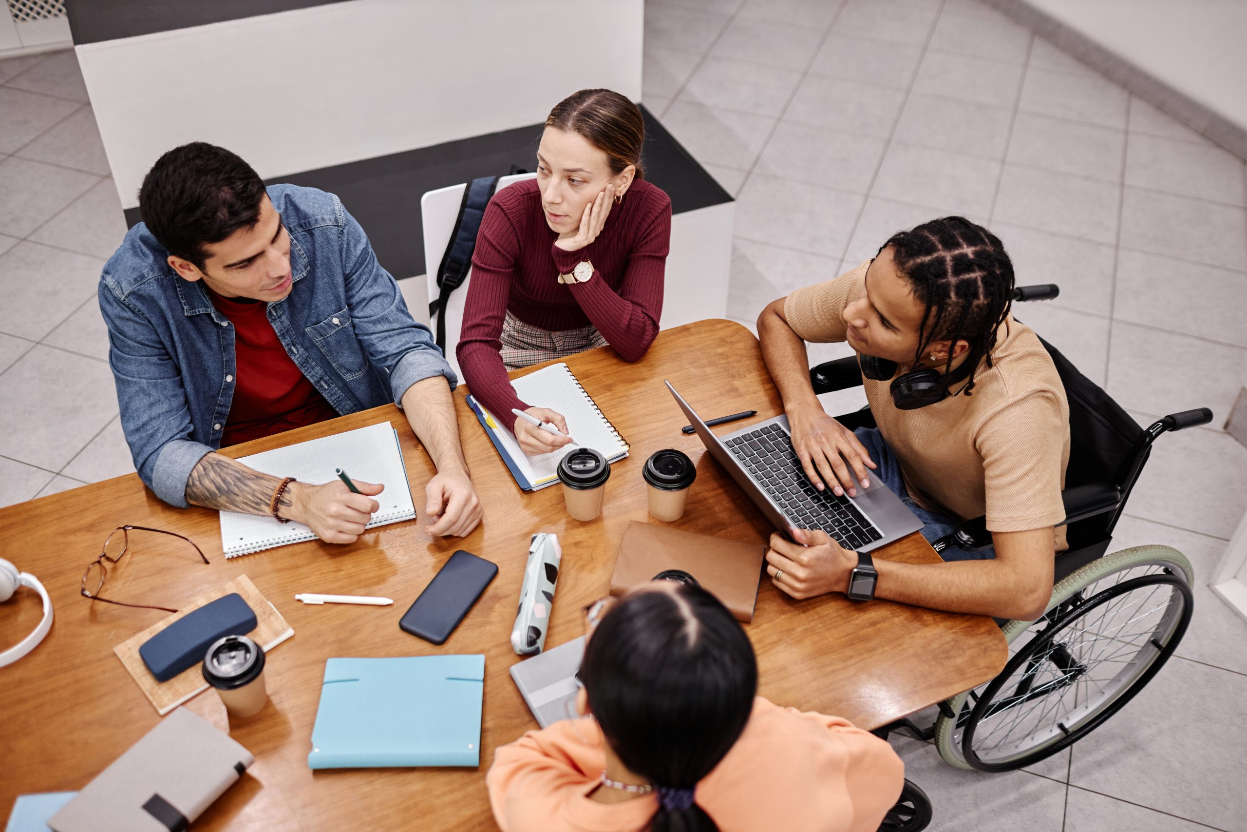 Diverse group of young people studying together in college library.