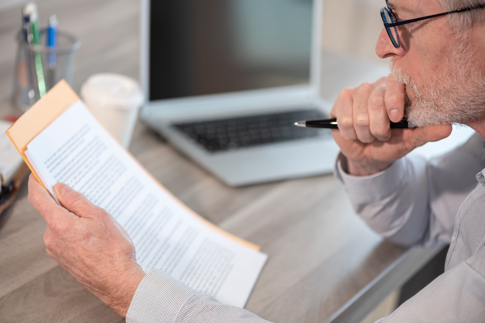 Person reviewing disability documentation at a desk with a laptop nearby.