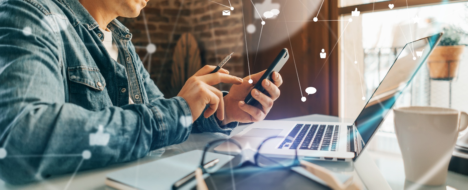 Person using a smartphone beside a laptop, with digital communication icons shown across the image.